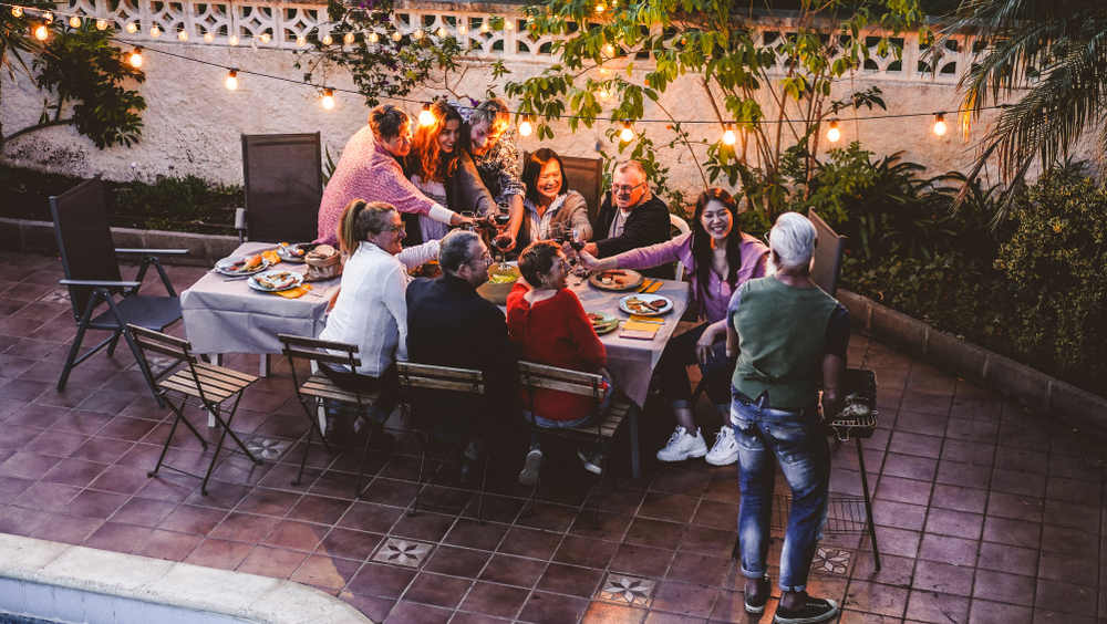 Happy family eating and cheering with red wine at barbecue party dinner